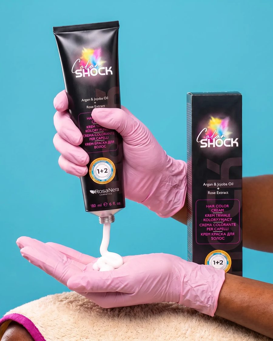 Gloved hands dispensing RosaNera Color Shock permanent color cream from the tube into a gloved palm, with the carton alongside